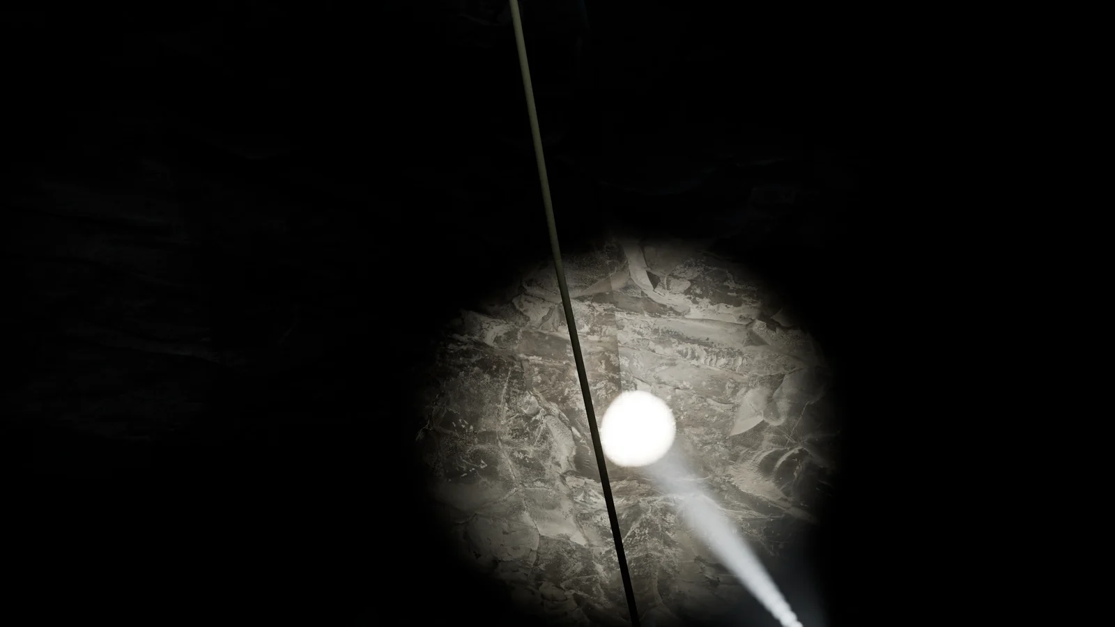 Torch illuminating underwater rock beside a vertical shot line